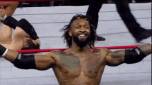 a man in a wrestling ring with his arms outstretched and a man laying on the ground behind him .