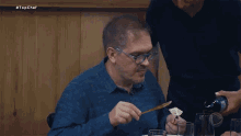a man is sitting at a table with a bottle of wine and a sign that says top chef
