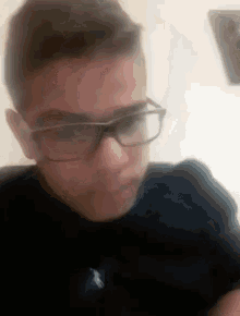 a young boy wearing glasses and a polo shirt is looking at the camera .