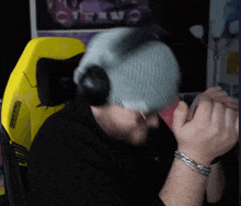 a man wearing a beanie and headphones sits in front of a yellow chair that says ' nintendo ' on it