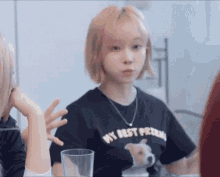a woman wearing a black t-shirt that says `` my best friend '' is sitting at a table with a glass .