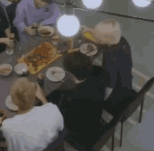a group of people are sitting at a table with plates of food .