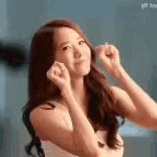 a woman with long hair is making a funny face with her hands .