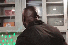 a man in a black shirt is standing in front of a glass cabinet with a box of cereal on it