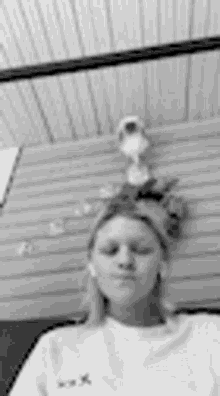 a black and white photo of a woman taking a selfie in front of a wall .