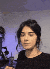 a woman in a black shirt is making a funny face while sitting in front of a computer .