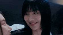 a woman with short black hair is smiling while looking at another woman .