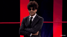 a man wearing sunglasses and a suit is standing in a boxing ring
