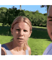 a man and a woman are standing in the grass and the woman is making a funny face