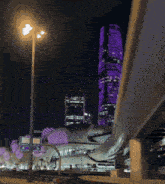 a purple skyscraper is lit up at night with a sign that says dubai