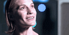 a close up of a woman 's face with blue lights in the background