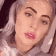 a close up of a woman 's face with purple hair and a piercing in her lip .