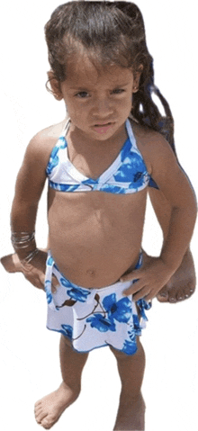 a little girl in a blue and white bikini stands on a white background