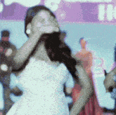 a woman in a white dress covers her face with her hands