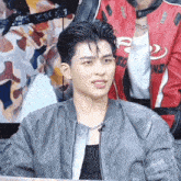 a man wearing a gray jacket and a red jacket with the letter r on it