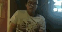 a man wearing glasses and a white t-shirt is sitting in front of a tv .