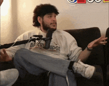 a man wearing a breckenridge shirt sits on a couch