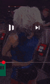 a woman in a blue top and black shorts is dancing in a ring .