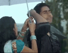 a woman is holding an umbrella over a man 's head in the rain .