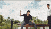 a man is sitting on a bench in front of a body of water .