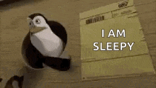 a penguin is sitting on top of a piece of paper and says `` i am sleepy '' .