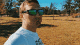 a man wearing sunglasses and a t-shirt that says ' ucsd ' on it stands in a field