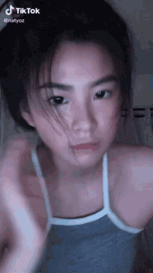 a girl is wearing a grey tank top and has a tiktok watermark
