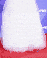 a woman in a white dress stands on a red carpet in front of a sign that says ' upbn '