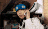 a woman wearing a sleep mask is talking on her cell phone