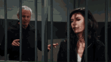 a man and a woman are behind bars in a jail