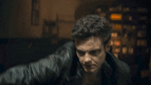 a man with curly hair is standing in a dark room with his arm raised in the air .