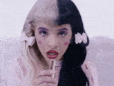 a girl with half blonde and half black hair is holding a lipstick in her hand