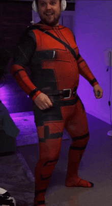 a man in a red and black deadpool costume with headphones on