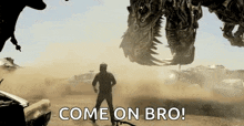 a man is standing in front of a giant robot that says come on bro !