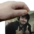 a hand is reaching out towards a man with headphones giving a thumbs up .