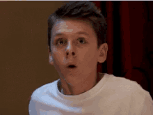 a young boy is making a surprised face with his mouth open .