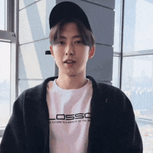 a young man wearing a black hat and a white t-shirt that says losso