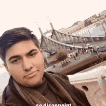 a young man taking a selfie with a bridge in the background