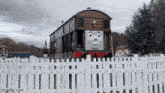 a train with a face on it is behind a white fence