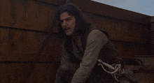 a man with long hair holds a sword in his right hand