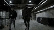 two men are walking in a dark warehouse with a sign that says ' e ' on it