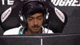 a man wearing blacklyte headphones sits in front of a monitor