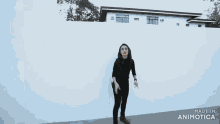 a woman walking in front of a white wall with the words made in animatica on the bottom right