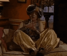 a woman in a costume is sitting on a couch smoking a cigarette .