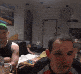 a man wearing a green hat with a bike on it is talking to another man