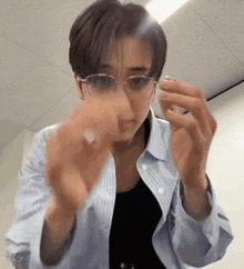 a man wearing glasses and a striped shirt holds something in his hands