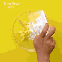 a person pouring cocoa powder into a glass bowl