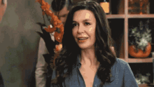 a woman in a blue shirt is smiling in front of a man