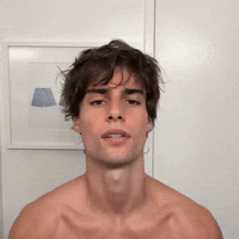 a shirtless man stands in front of a picture of a lamp