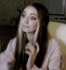 a woman wearing headphones and a pink sweater is sitting in a chair .